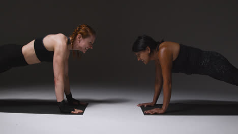 Studio-Shot-Of-Two-Mature-Women-Wearing-Gym-Fitness-Clothing-Doing-Plank-Exercise-Together-2